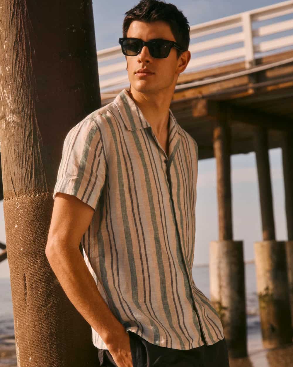 Man wearing a Rails short-sleeve vertical striped shirt with black sunglasses