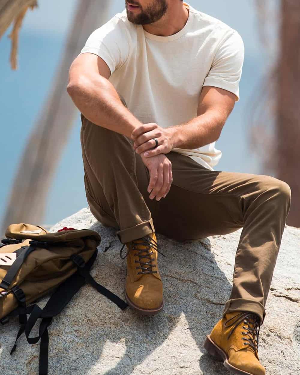 Man wearing Flint and Tinder white T-shirt, khaki green pants and tan suede lace up boots