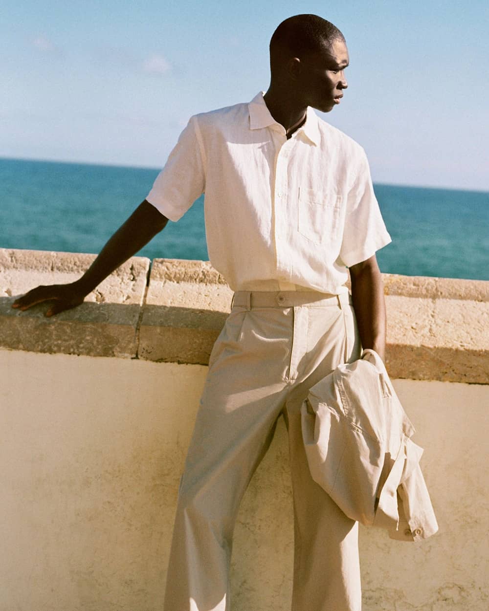 Black man wearing Arket beige cotton suit with a loose short-sleeve white linen shirt