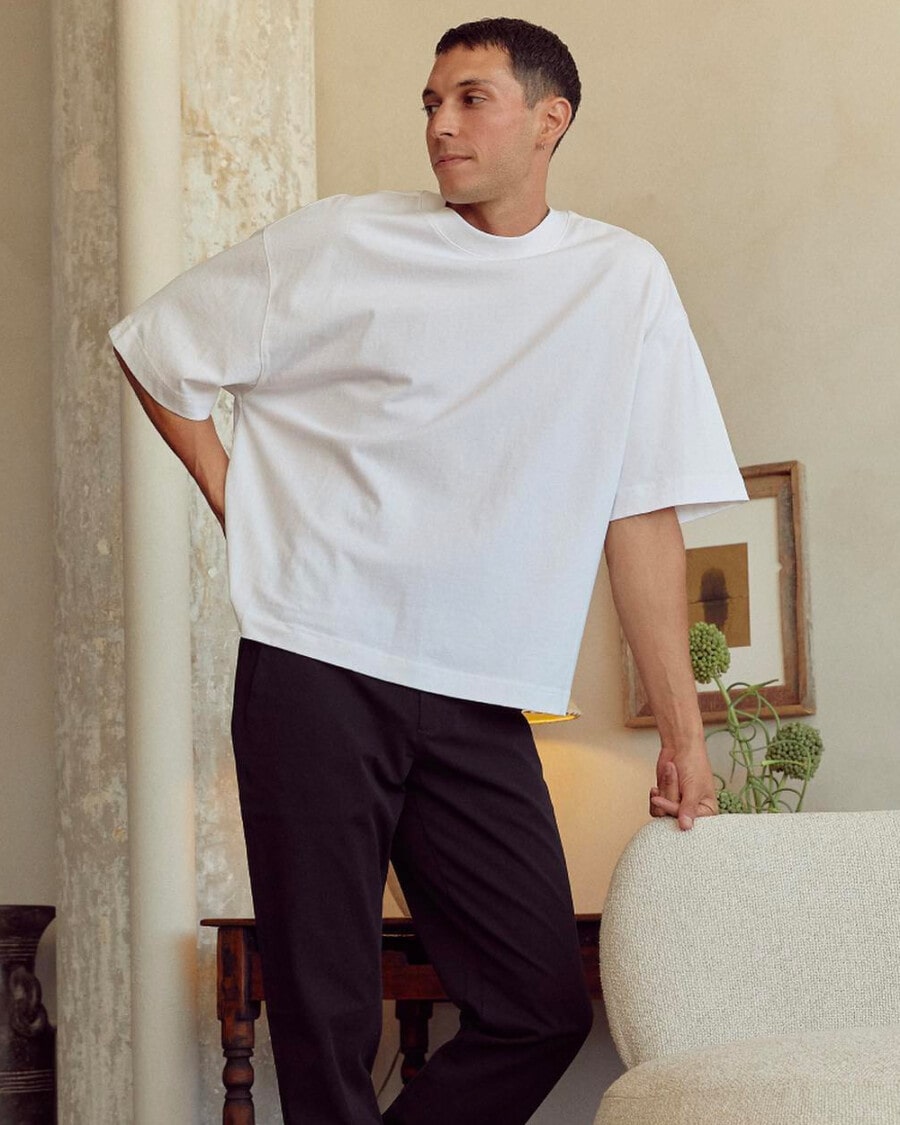 Man wearing a heavyweight, oversized white T-shirt by Everlane with black pants