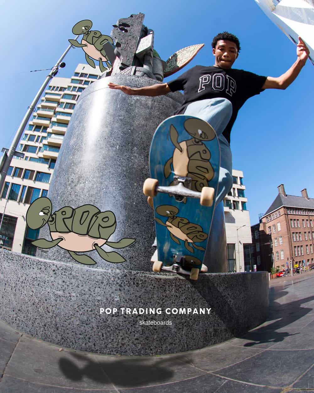 Black man on skateboard wearing a black Pop Trading Co logo T-shirt and pale wash jeans