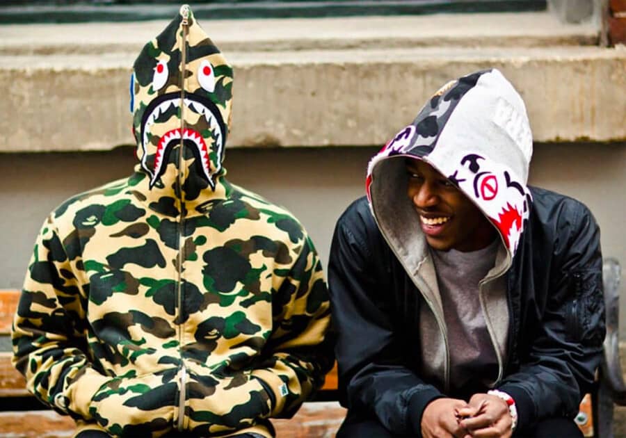 Two men wearing printed BAPE hoodies - one in camo and the other in grey