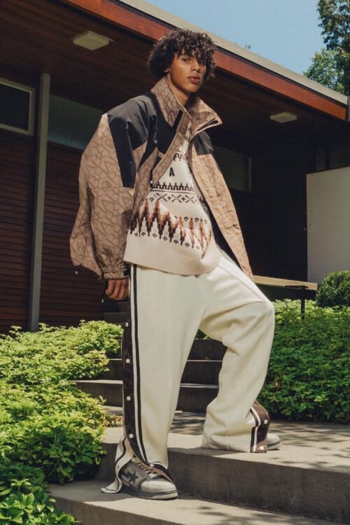Man wearing A Bathing Ape / BAPE loose popper pants, patterned oversized sweater, an all over printed logo jacket and chunky skate shoes