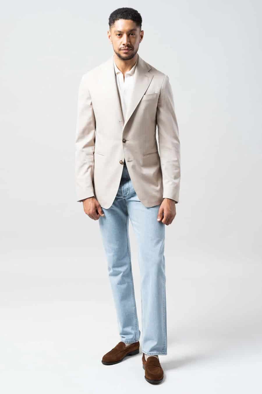 Men's pale blue wash jeans, white polo shirt, beige blazer and brown suede penny loafers outfit