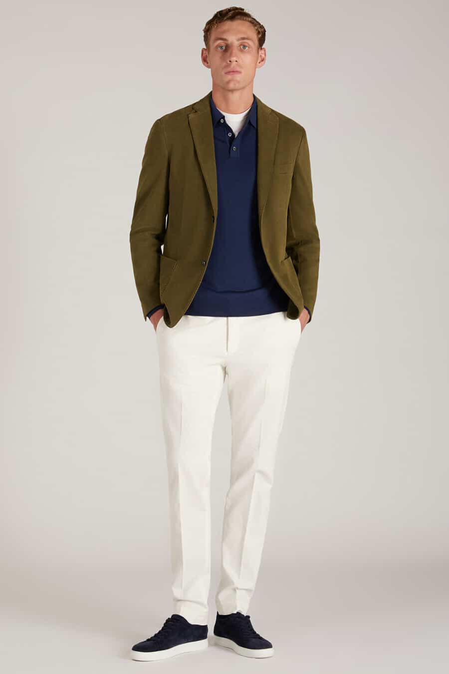 Men's white pants, navy polo shirt, olive blazer and navy sneakers