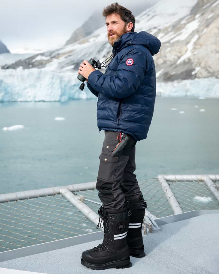 Man wearing Canada Goode snow pants and snow boots with a blue padded down jacket
