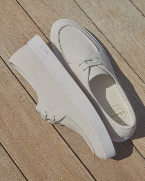 A pair of Church's Longsight Nubuck Sneakers in Bright white on a deck