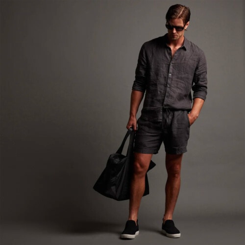 Man wearing James Perse charcoal lightweight linen shorts with a matching shirt and black sneakers
