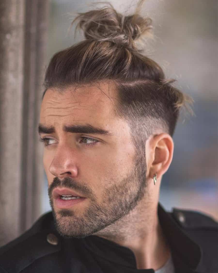 Man with a long top knot hairstyle and taper fade sides
