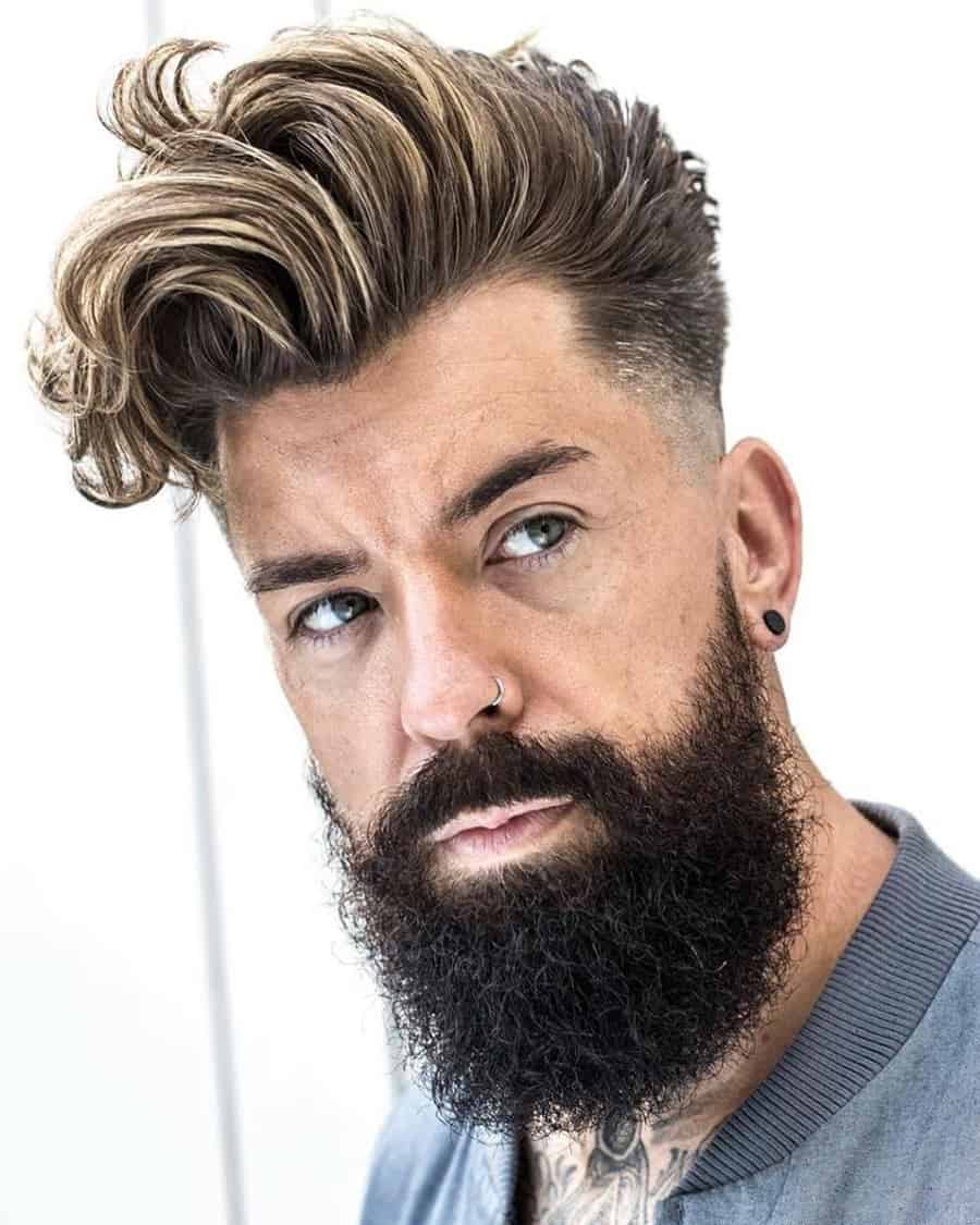 Man with a long highlighted quiff haircut and low fade, plus bushy beard