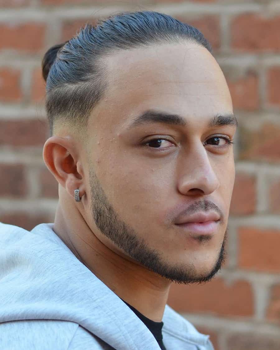 Man with long man bun hairstyle and low skin fade