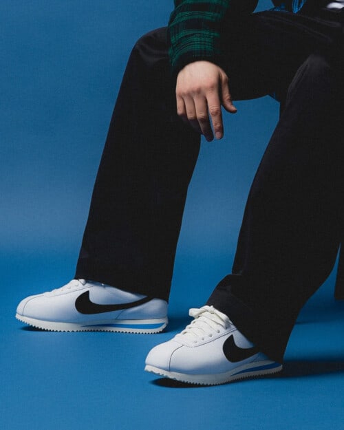 Nike Cortez in white worn on feet with loose black pants