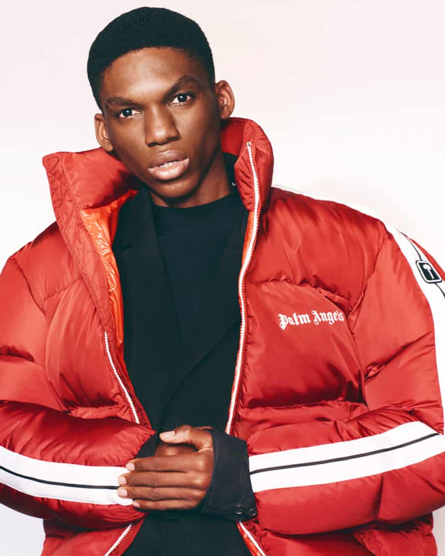 Man wearing padded red Palm Angels puffer jacket with white stripes over a black sweatshirt