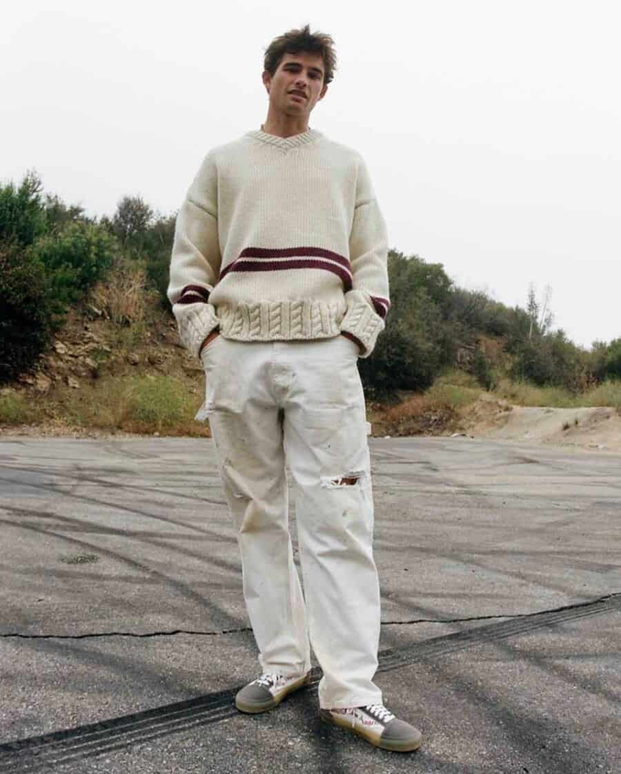 Man wearing white Palm Angels knit sweater, loose white pants and canvas sneakers