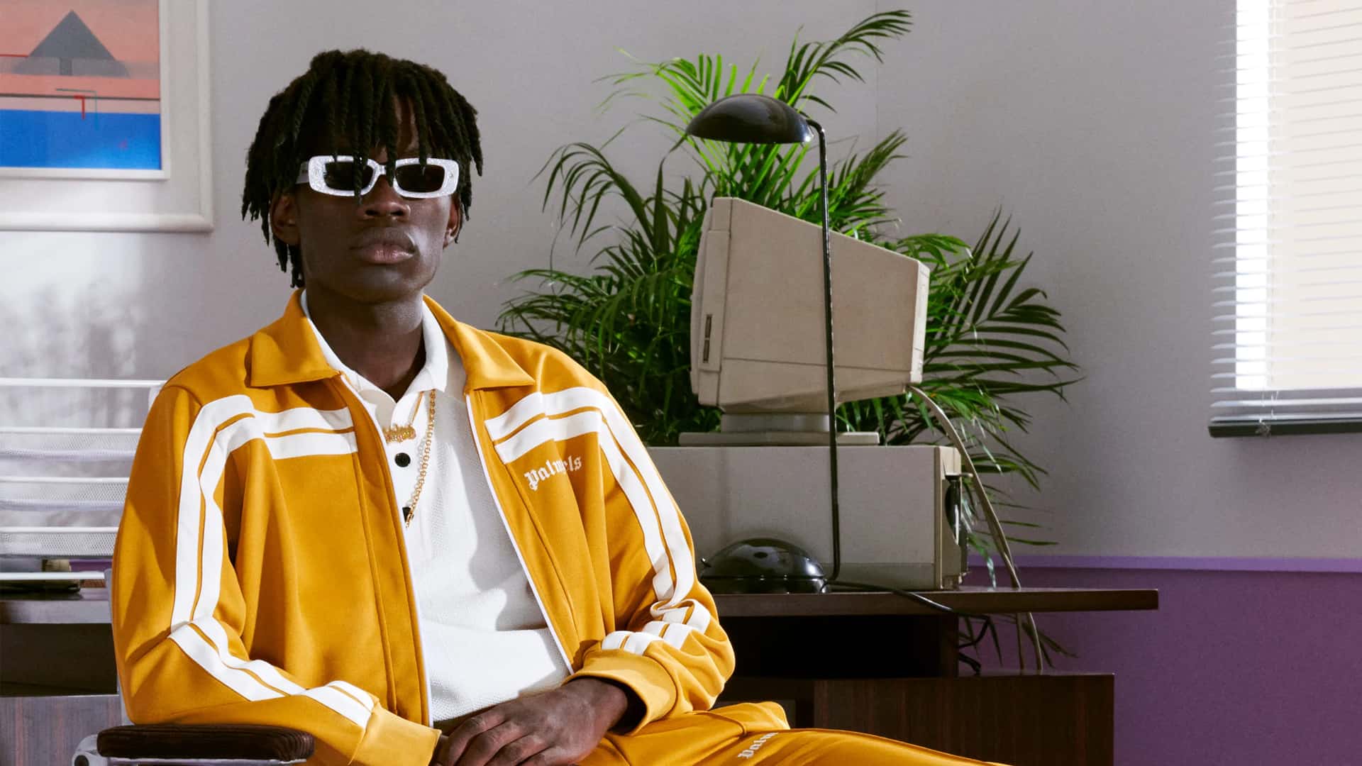Man wearing full yellow Palm Angels tracksuit with white polo shirt and sunglasses