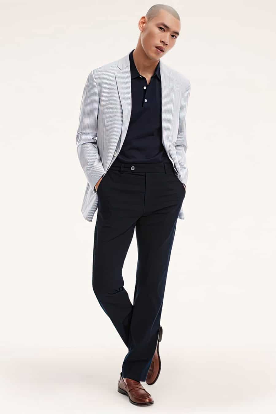 Men's navy pants, navy polo shirt, light blue seersucker blazer and tan leather penny loafers outfit