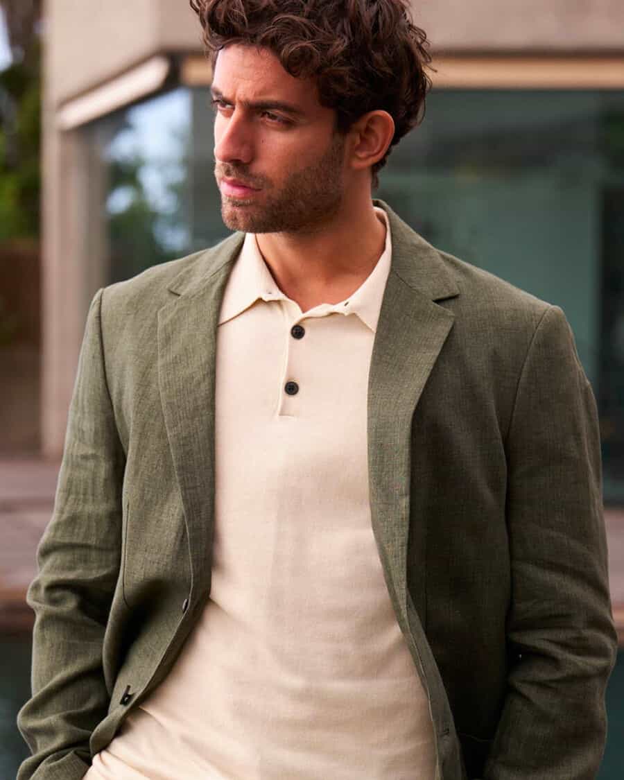 Man wearing an off-white polo shirt underneath an unstructured green linen blazer