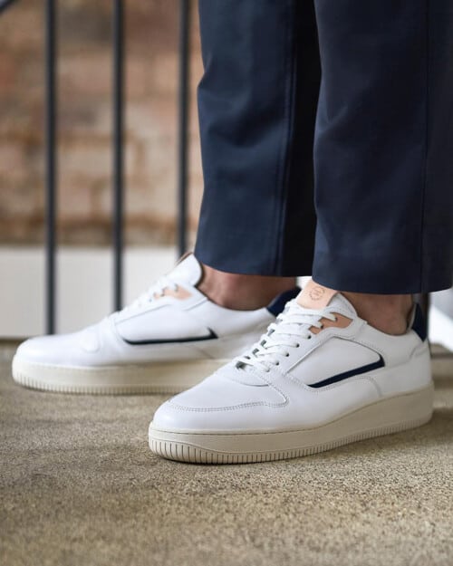 Men's white Uniform Standard Series 5 sneakers worn on feet with no socks and cropped navy pants