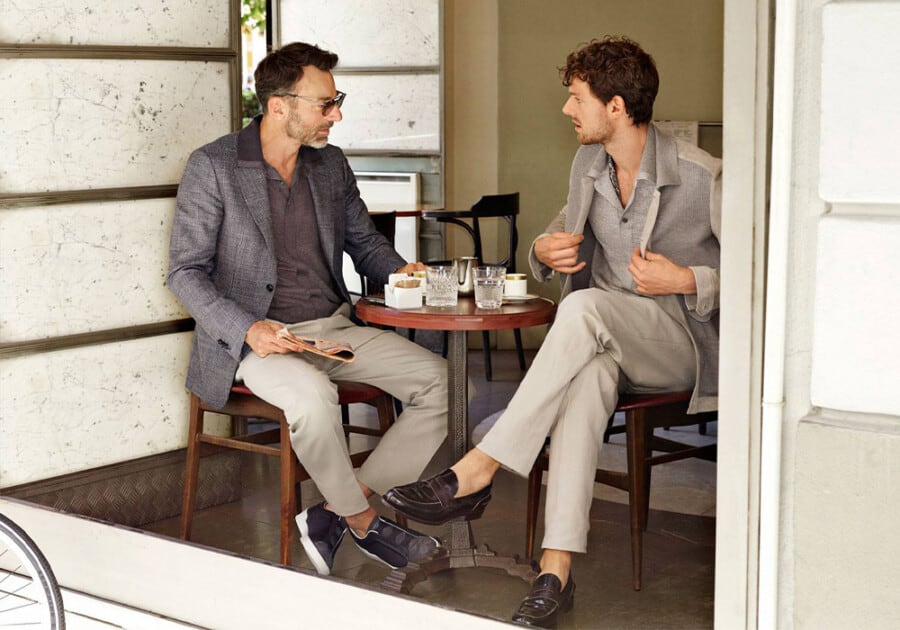 Two men sitting having coffee wearing suit separates (blazer and trousers) with polo shirts