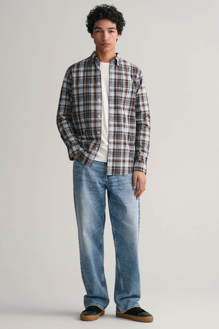Men's light-wash baggy jeans, white T-shirt, brown/blue check shirt and black gum sole sneakers outfit