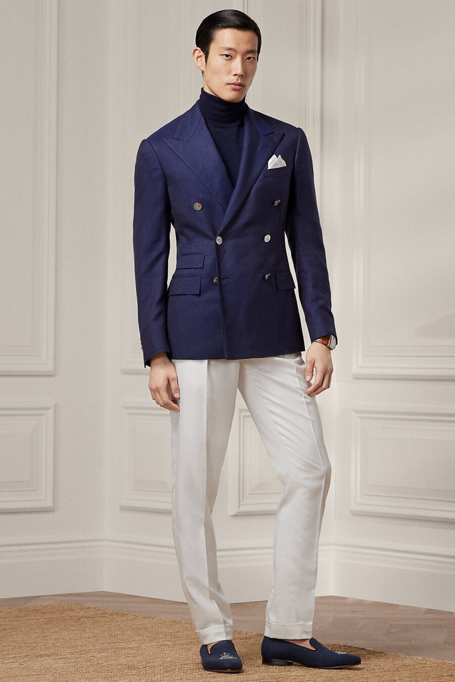 Men's double-breasted navy blazer, light grey tailored pants, navy turtleneck and navy dress slippers outfit
