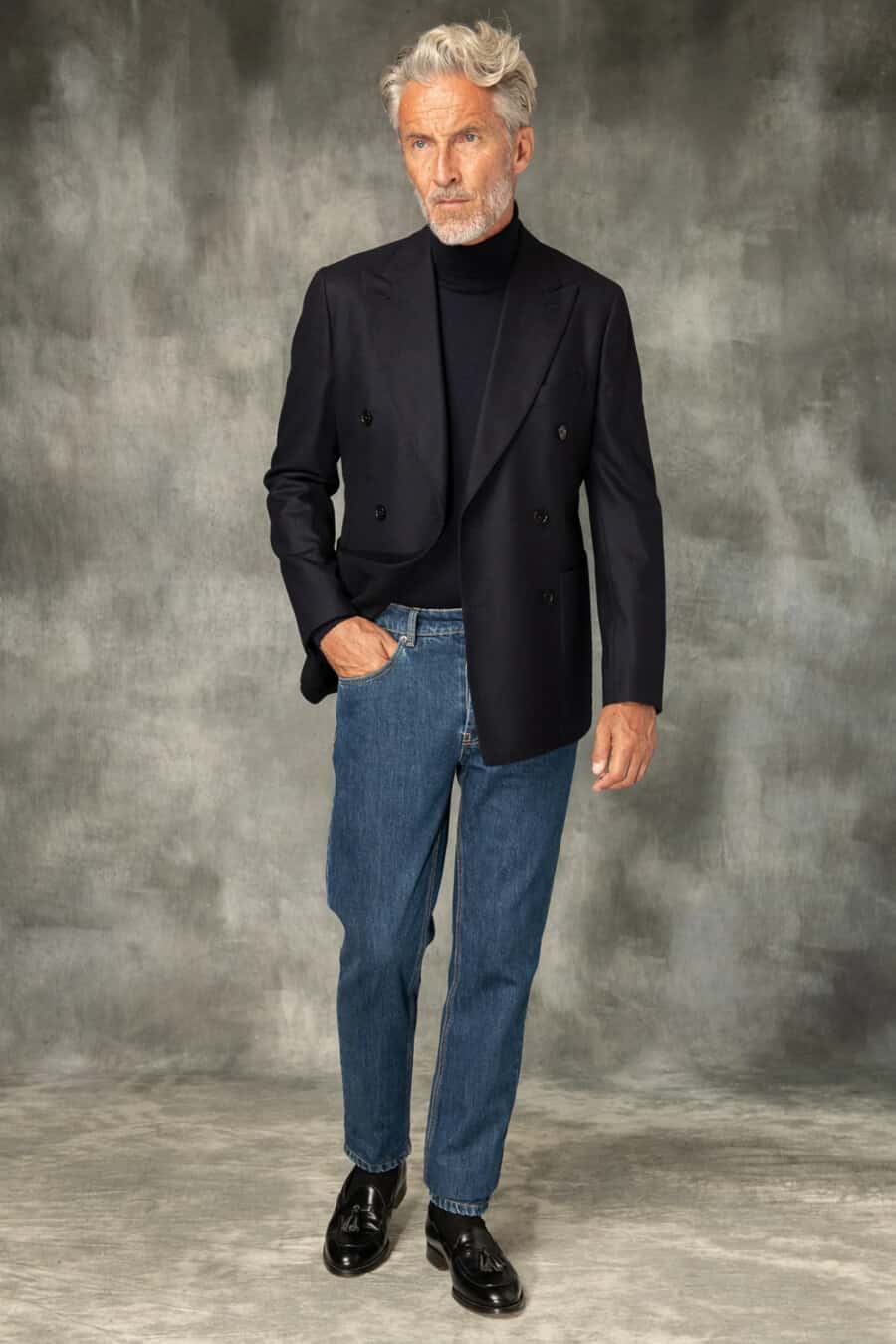 Men's navy double-breasted blazer, mid-wash jeans, navy turtleneck and black leather tassel loafers outfit