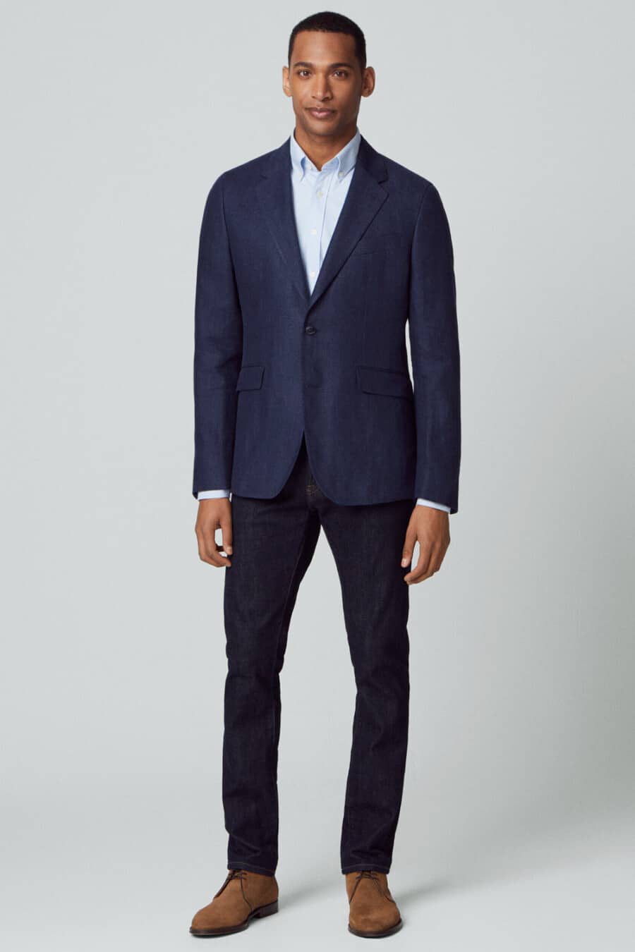 Men's Navy single-breasted blazer, dark raw denim jeans, sky blue shirt and tan suede chukka boots outfit