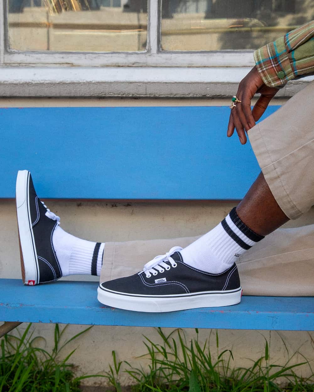 Man wearing black Vans skate shoes on feet with white tube socks