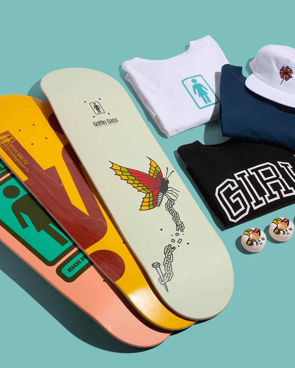Selection of Girl skateboards and T-shirts laid on blue background