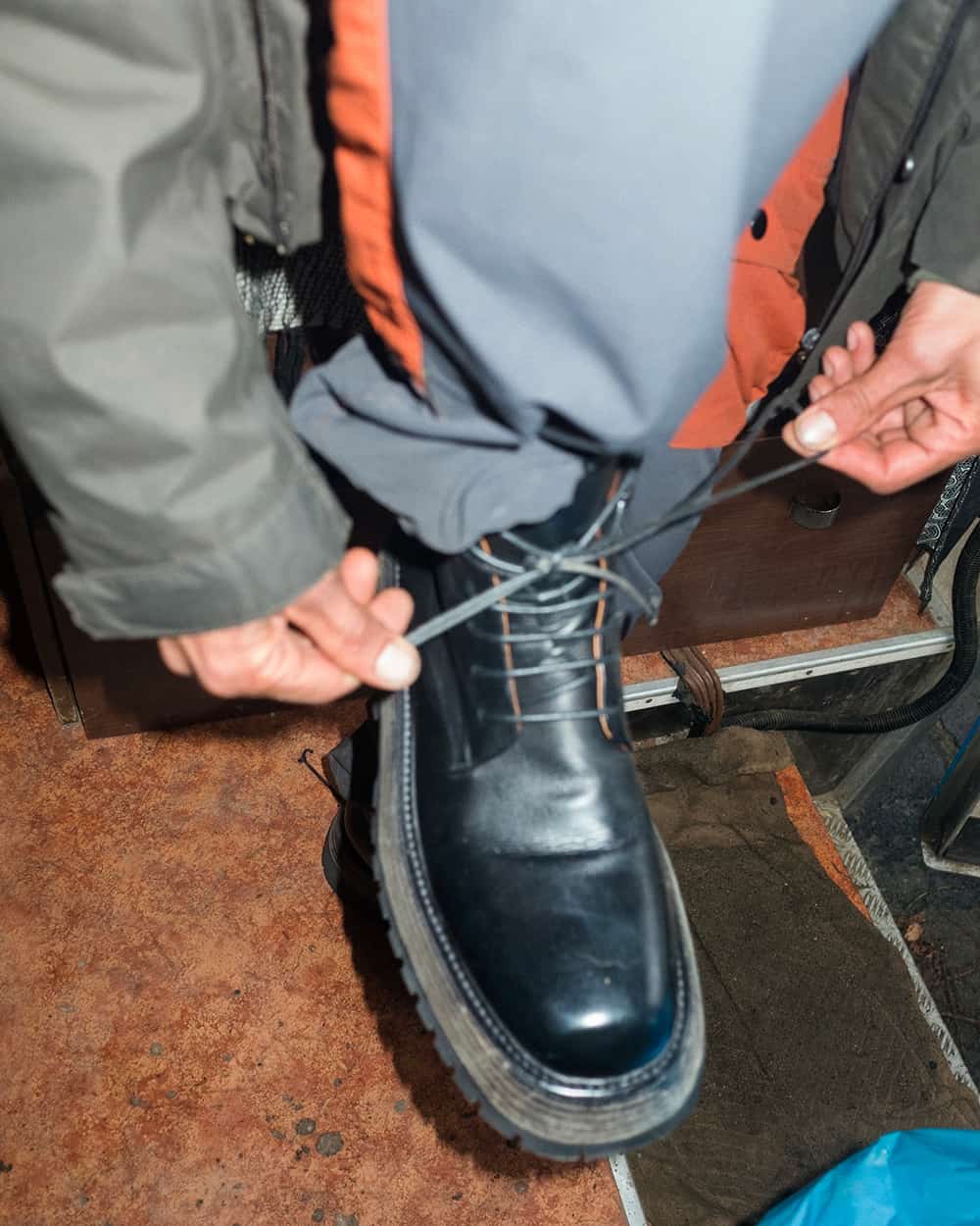 Man tying up a pair of chunky black leather boots by Marsell