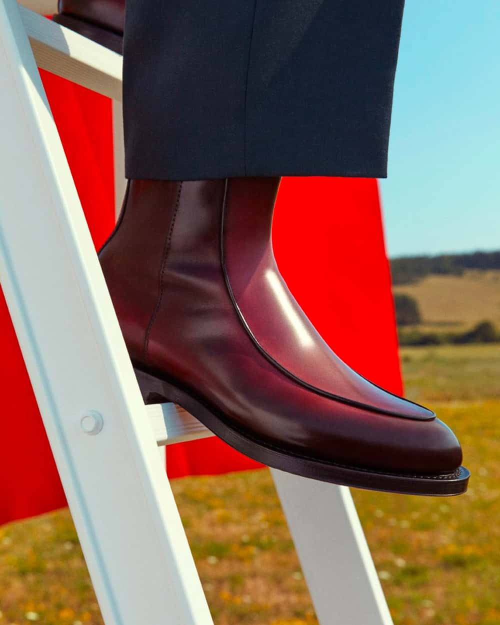 Men's burgundy Santoni boots worn on feet with navy pants