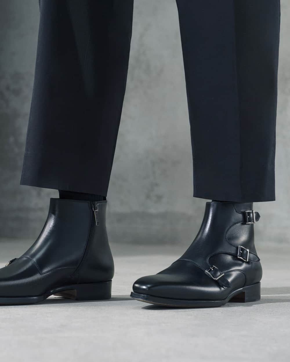 A pair of men's Magnanni black triple buckle Chelsea boots worn on feet with cropped black pants