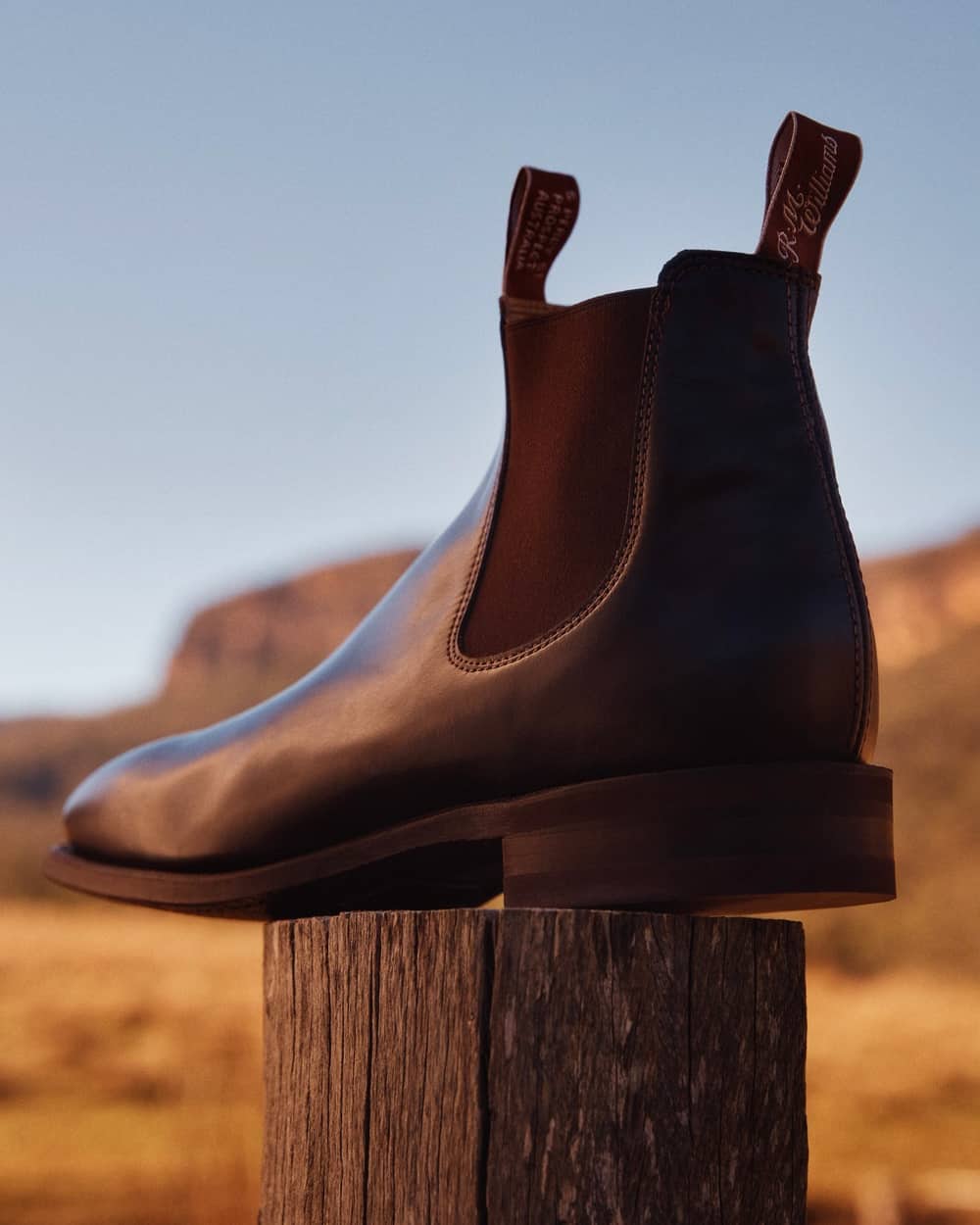 An R.M.Williams men's brown leather Chelsea boots outside on top of a fence post
