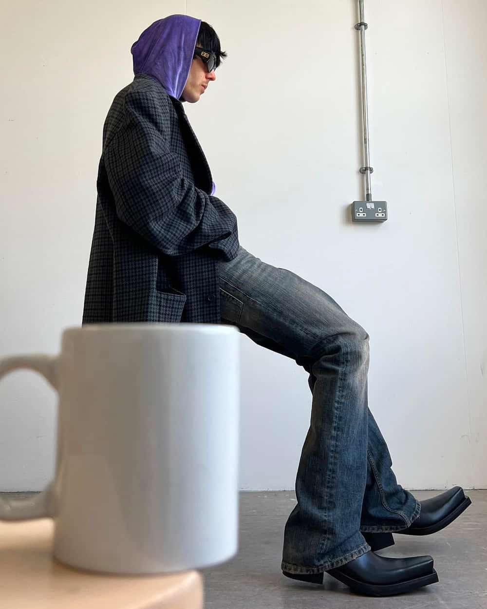 Man wearing Balenciaga purple hoodie, black check coat, black denim jeans and black heeled boots