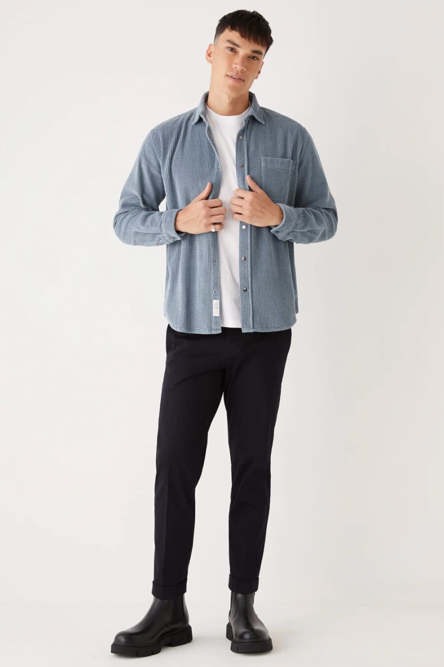 Men's black pants, white T-shirt, light blue corduroy shacket and black chunky Chelsea boots outfit