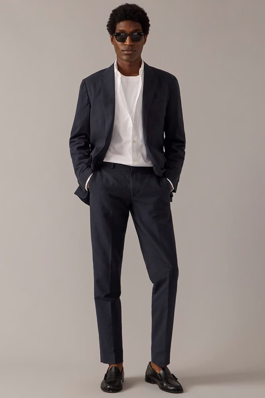 Men's navy suit, white T-shirt, white shirt, black sunglasses and black leather penny loafers worn sockless outfit