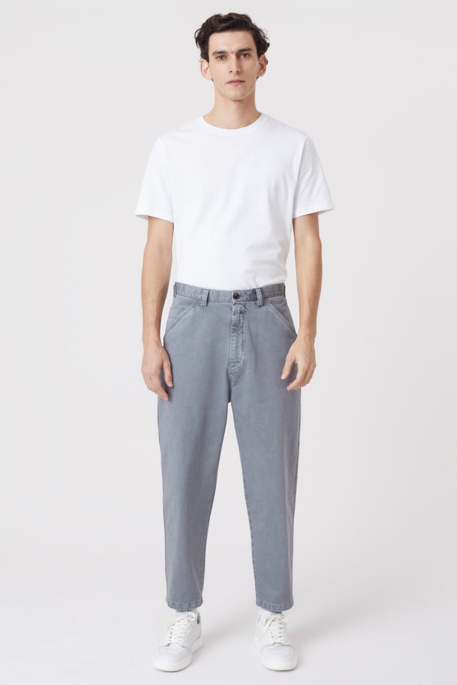 Men's grey wide-leg carrot pants, tucked in white T-shirt and white sneakers outfit