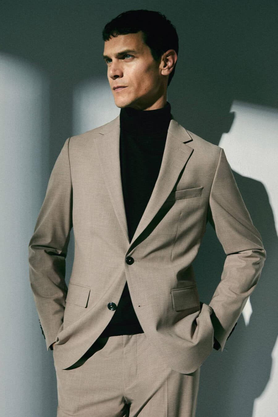 Man wearing a brown suit with a black turtleneck