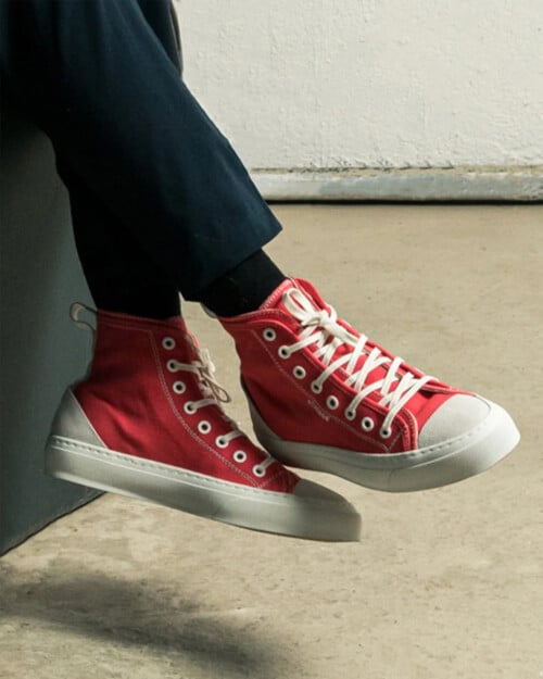 DiVERGE Twist Hi Canvas Sneaker in red worn on feet with navy pants and black socks