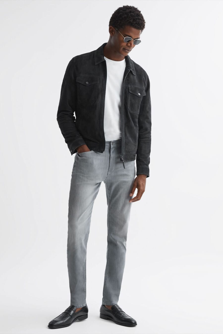 Men's grey jeans, white T-shirt, black suede jacket and black leather penny loafers worn sockless outfit