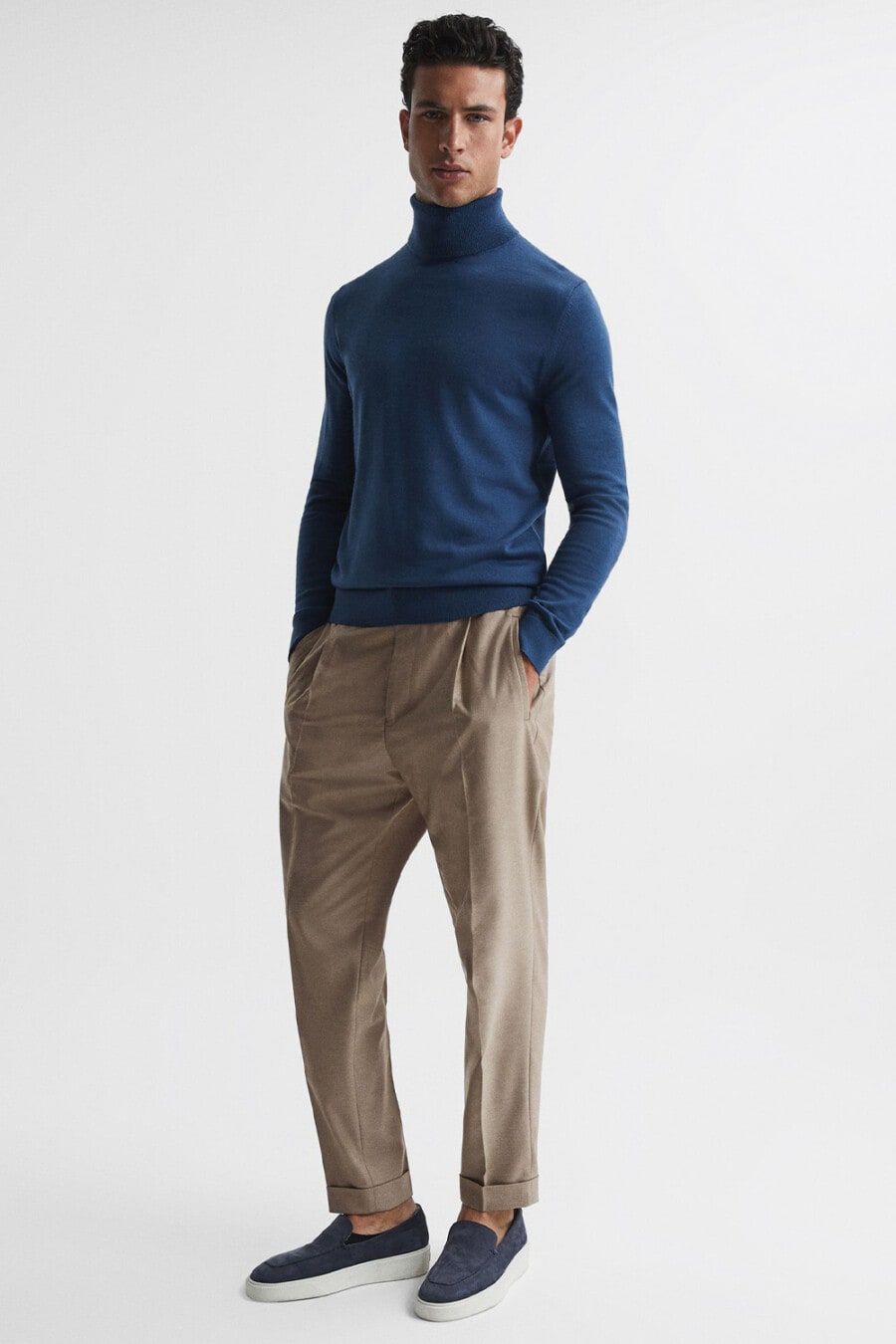Men's pleated khaki pants, blue turtleneck and navy suede slip on shoes outfit
