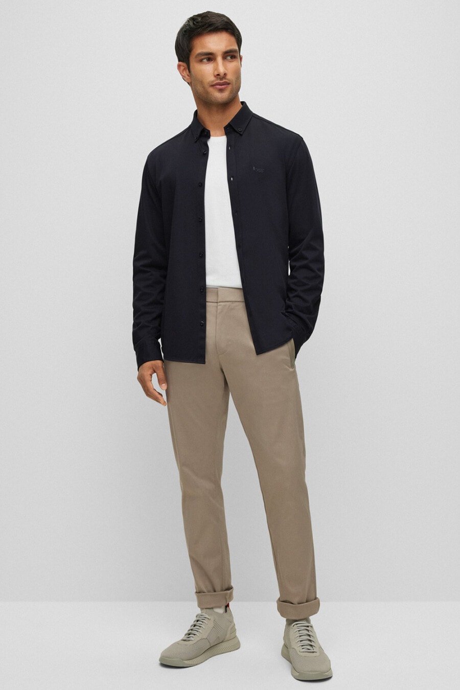 Men's khaki pants, white tucked in T-shirt, navy blouson jacket and grey suede sneakers outfit