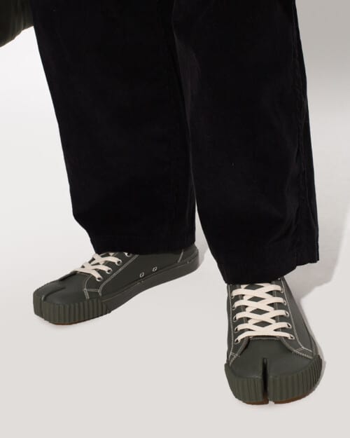 Maison Margiela Tabi split toe low-top sneakers in green worn on feet with baggy black pants