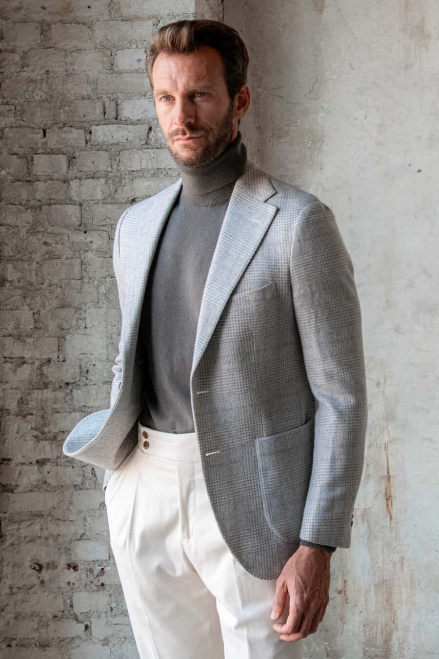 Man wearing white pants, grey turtleneck and light grey check blazer