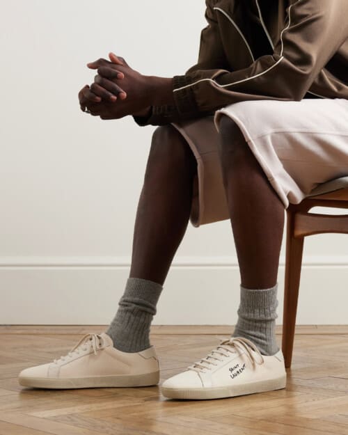Saint Laurent Court Classic SL/06 canvas sneaker worn on feet with grey socks and beige jersey shorts