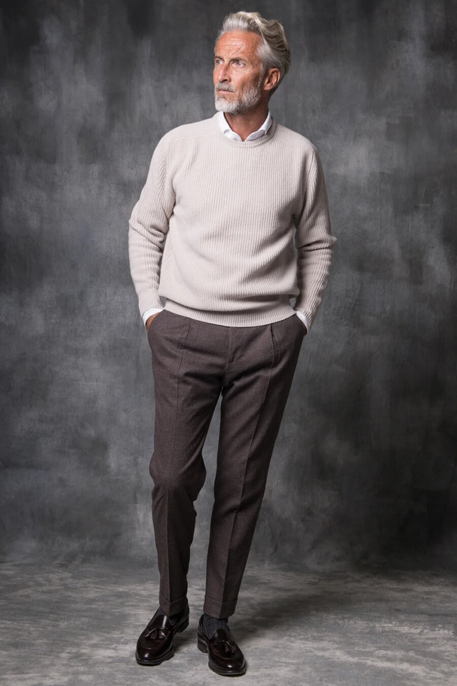 Men's tailored brown pants, white shirt, stone grey ribbed sweater, grey socks and brown leather tassel loafers outfit