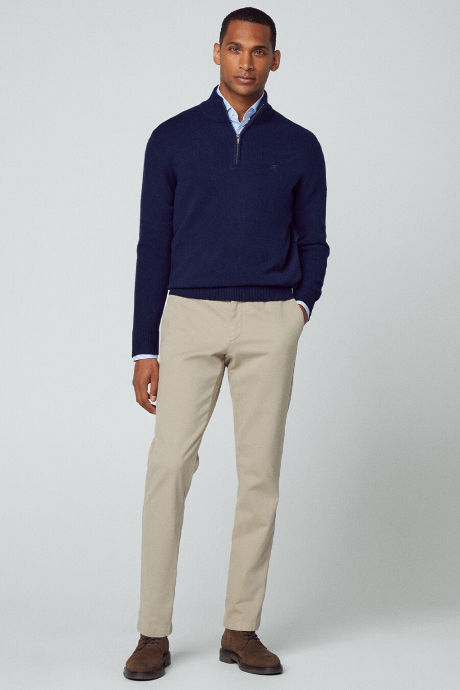 Men's khaki pants, light blue shirt, navy half-zip sweater and brown suede shoes outfit