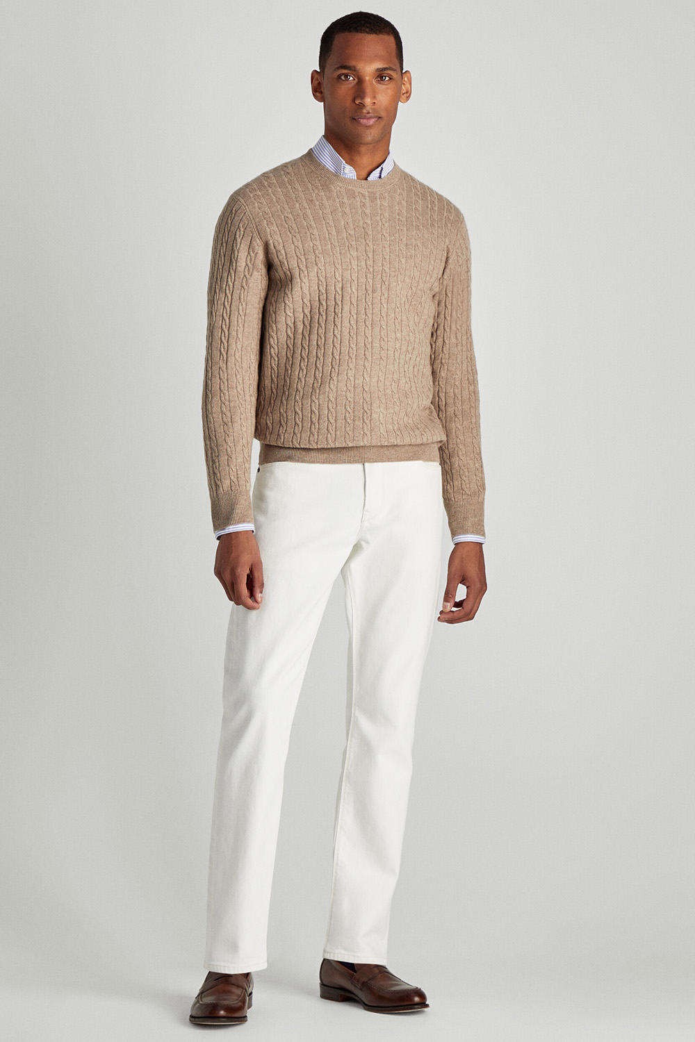 Men's white jeans, blue pinstripe shirt, camel cable knit sweater and brown leather penny loafers outfit