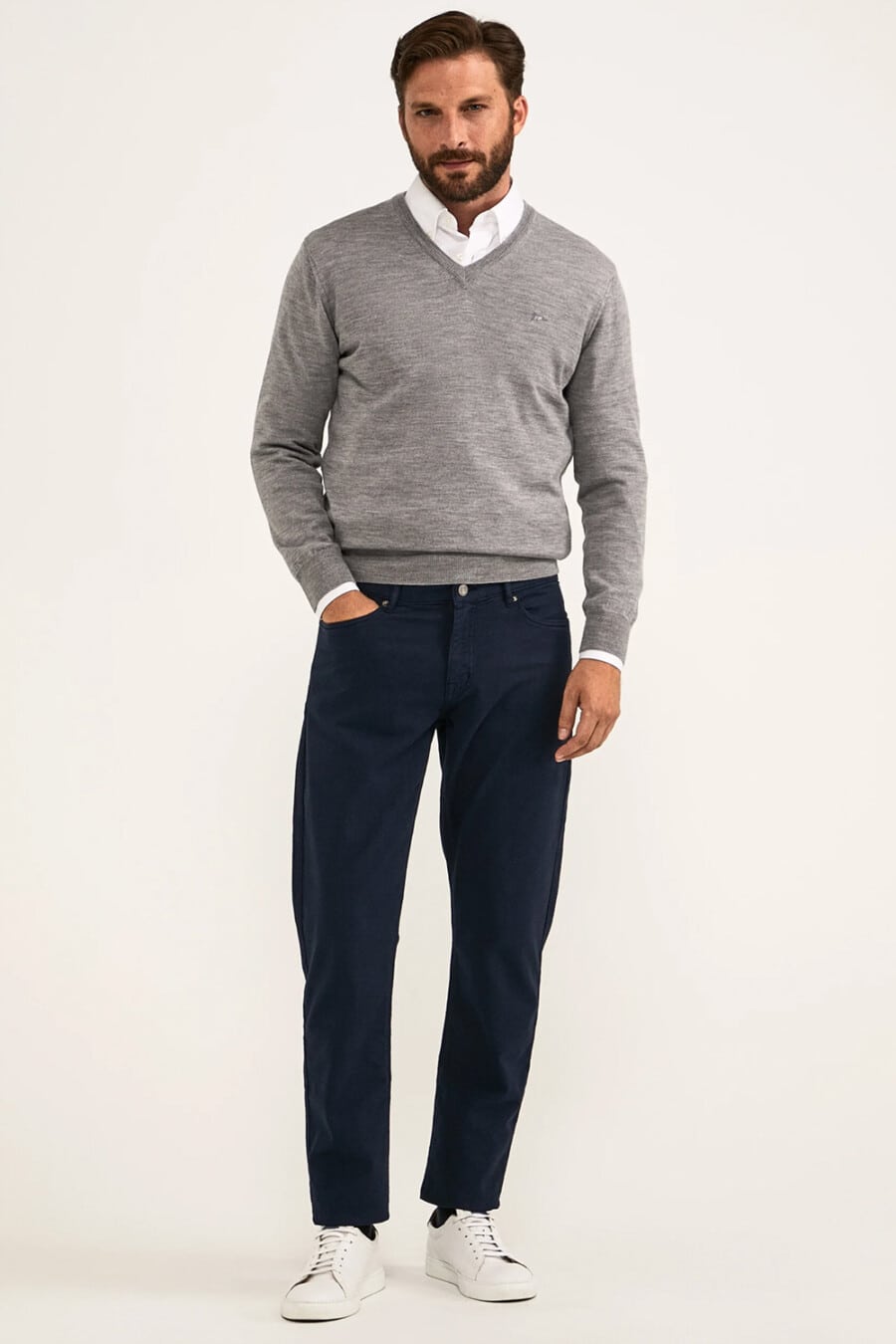 Men's navy chinos, white shirt, grey V-neck merino sweater and white sneakers outfit