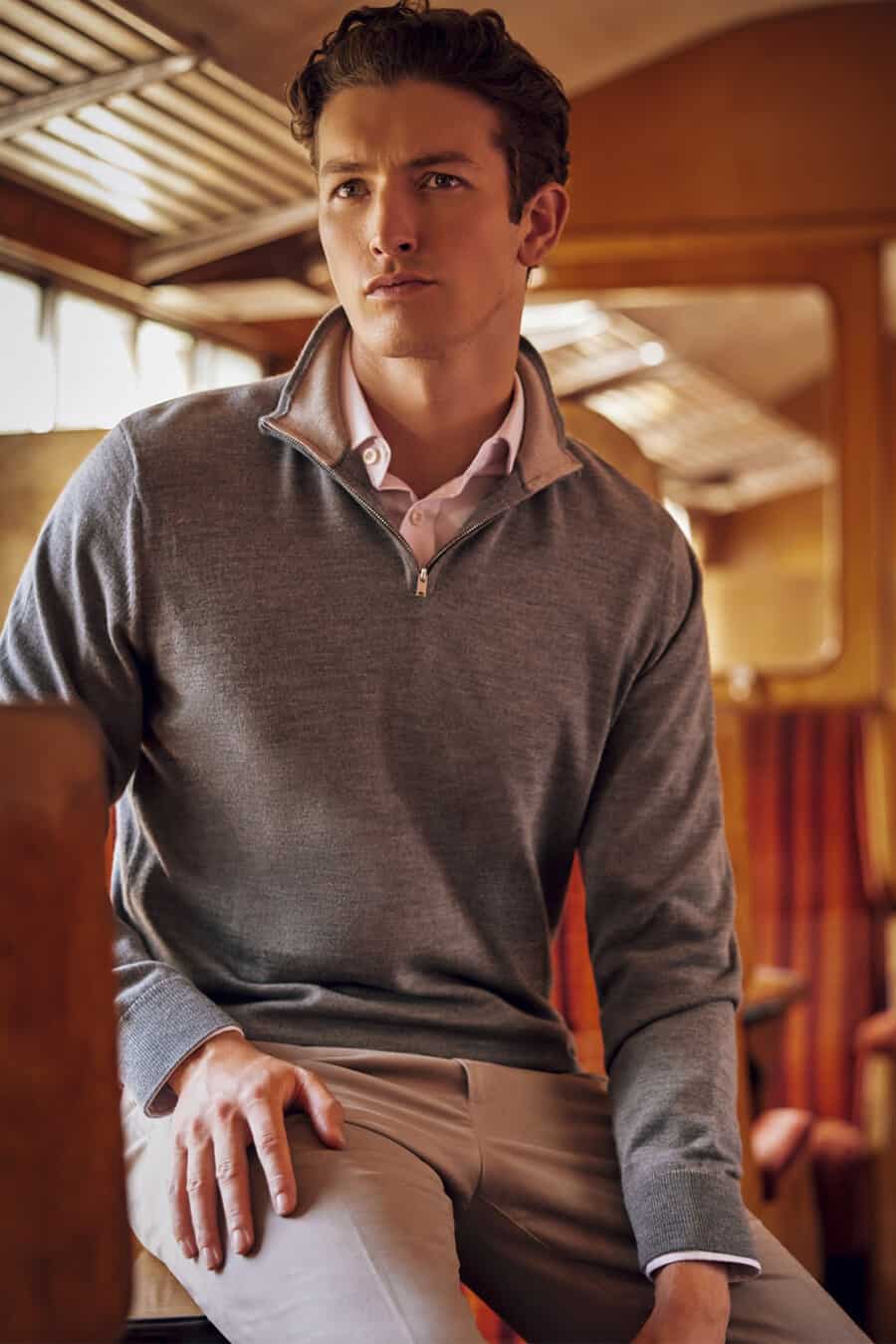 Man wearing pink soft collar shirt underneath a grey quarter-zip sweater with grey chinos